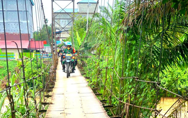 Sosialisasi Pemilu Damai, Kapolres Rohul dan Babinsa TNI Naik Sepeda Motor Lewati Jembatan Aek Matua